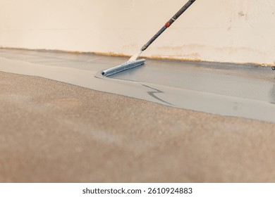 Worker applying epoxy flooring system with a notched squeegee