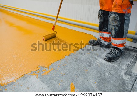Worker applying epoxy and polyurethane flooring system.These easy-to-clean products also have non-slip features.