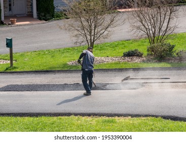 Worker Applying A Layer Of Tarmac Or Extra Blacktop To Repair Damage To Asphalt Street