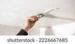 Worker is applying putty on a ceiling. Renovating house 