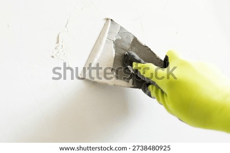 Worker Applying Wall Putty With A Spatula While Smoothing The Wall