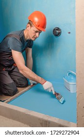 The Worker Is Applying Waterproofing Paint To The Floor In The Bathroom.