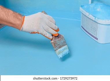 A Worker Is Applying Waterproofing Paint To The Floor In The Bathroom.