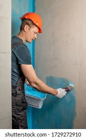 The Worker Is Applying Waterproofing Paint To The Wall In The Bathroom.