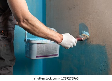 A Worker Is Applying Waterproofing Paint To The Wall In The Bathroom.