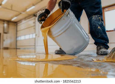 Worker Applying A Yellow Epoxy Resin Bucket On Floor.