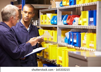 Worker And Apprentice Checking Stock Levels In Store Room