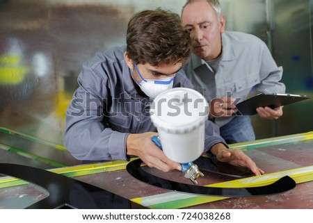 worker and apprentice learning to spray painting