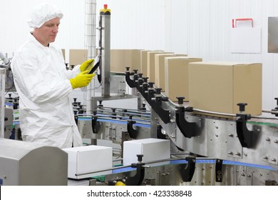 worker in apron, cap with tablet, at production line in factory
