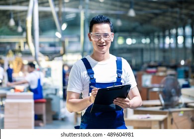 Worker In Asian Production Plant Or Factory Working On Checklist With Clipboard
