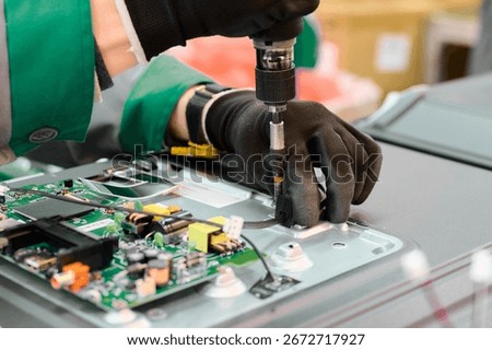 Worker assembling electronic components in a television manufacturing plant during daytime operations