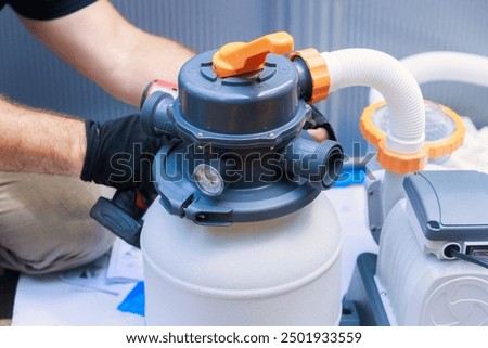 Worker assembling sand filter system tank, equipment for cleaning swimming pools