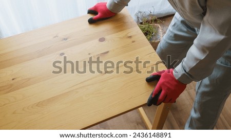 A worker assembling a table. A worker collects unnecessary items.