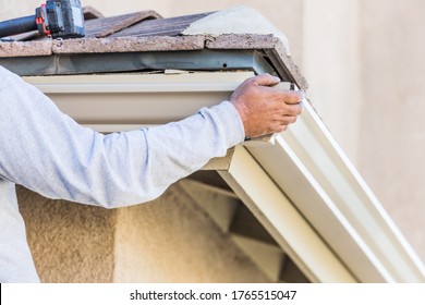 Worker Attaching Aluminum Rain Gutter To Fascia Of House.