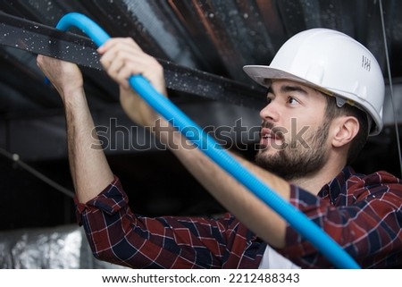 worker in the attic connects metal air ducts