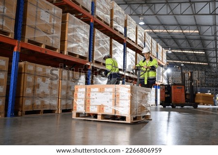 Worker in auto parts warehouse use a handcart to work to bring the box of auto parts into the storage shelf of the warehouse waiting for delivery to the car assembly line