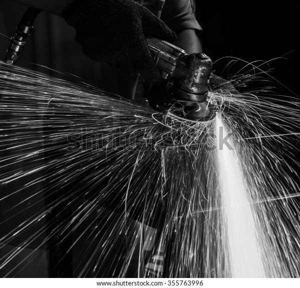 worker in automotive industry grinding metal body\
car with sparks  black\
white