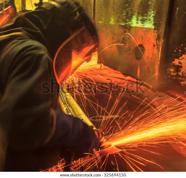 worker in automotive industry  grinding movement\
metal body car with\
sparks
