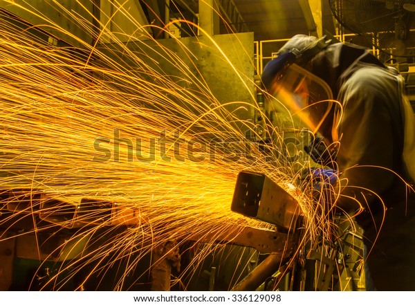 worker in automotive industry movement work\
grinding parts with\
sparks