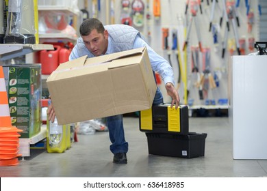 worker with backache while lifting box in the warehouse