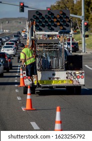 Worker Behind Utility Truck Placing Bright Orange Traffic Cones On Roadway For Traffic Control At An Accident Scene