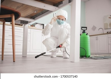 Worker In Biohazard Suit Disinfecting House