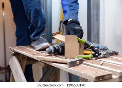 Worker In Blue Dirty Uniform, Scaffolding, Construction Tools, Puncher, Level, Against Background Of Construction Site And Renovation In The Kitchen Of Restaurant