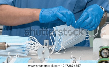 Worker in Blue Gloves Assembles Face Masks on a Production Line