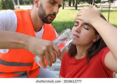 Worker With Bottle Of Water Helping Woman Outdoors. Suffering From Heat Stroke