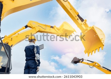 Worker builder with digital tablet controls process work of truck and excavator. Concept industry building with AI technology.