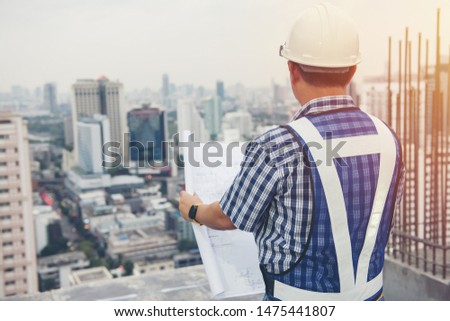 The worker builder foreman engineering occupation working with construction site project background. person looking plan paper to made floor business tower building. industry achitecture building.