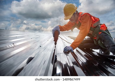worker builder with hand drill at metal profile roof installation Metal roof construction