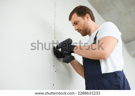 Worker builder installs plasterboard drywall at a construction.