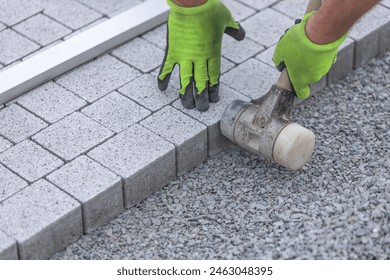 Worker building a sidewalk, laying interlocking pavers, walking path, industrial concept