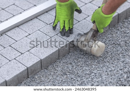 Worker building a sidewalk, laying interlocking pavers, walking path, industrial concept