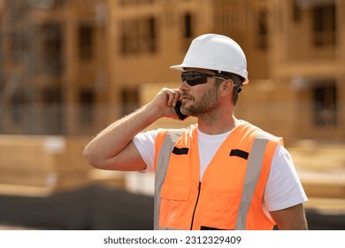 Worker call with phone in building uniform on buildings construction background. Builder at the construction site. Man worker with helmet on construction site. Bilder in hardhat. - Powered by Shutterstock