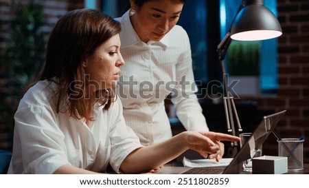Worker calling manager at workstation to look over paperwork and give feedback on company project. Businesswoman brainstorming with team leader, looking over accounting figures on laptop