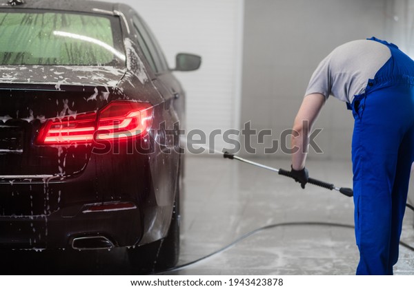 Worker at Car Wash Shop, Using Pressure\
Washer on Car, man washing car with a\
foam.