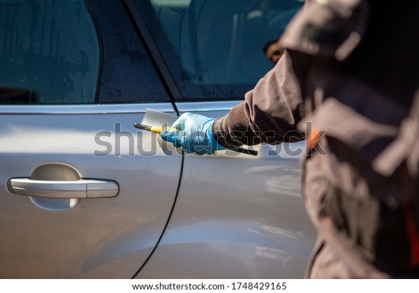 A\
worker in a car wash wipes the car and the windows. The worker\
wears blue rubber sneakers. Car wash. Copy\
Space.