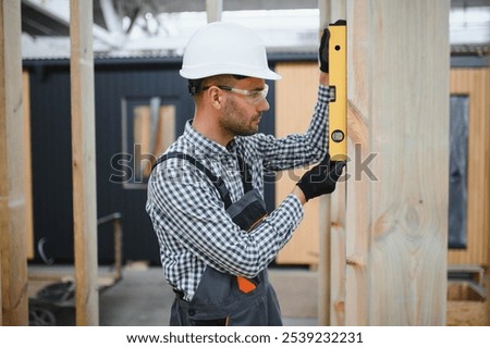 Worker carpenter assembling a modular house.