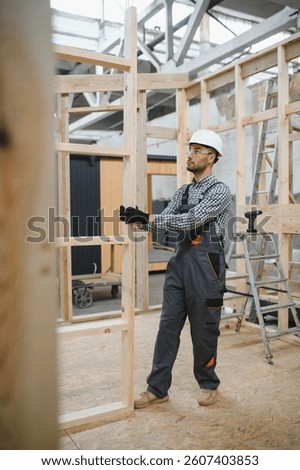 Worker carpenter assembling a modular house.
