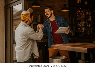 Worker carrying barrel with beer at the brewery and talking to the brewery owner - Powered by Shutterstock