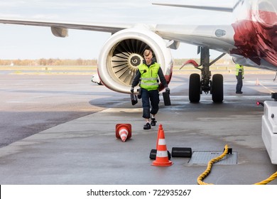 Worker Carrying Chocks By Airplane On Wet Runway