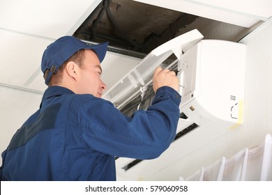 Worker Carrying Out Maintenance Of Air Conditioner In Office