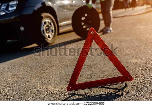 Worker changes a broken wheel of a\
car. The driver should replace the old wheel with a\
spare