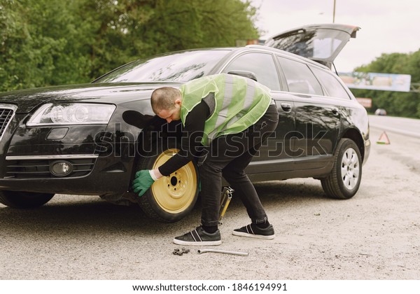 Worker changes a broken wheel of a car. The\
driver should replace the old wheel with a spare. Man changing\
wheel after a car\
breakdown.