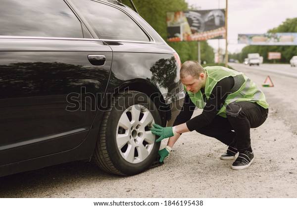 Worker changes a broken wheel of a car. The\
driver should replace the old wheel with a spare. Man changing\
wheel after a car\
breakdown.