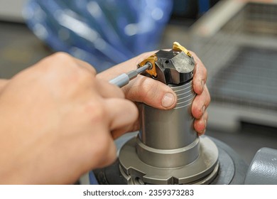 A worker changes a high speed insert on a milling cutter to work on a CNC milling machine