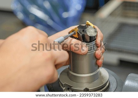 A worker changes a high speed insert on a milling cutter to work on a CNC milling machine