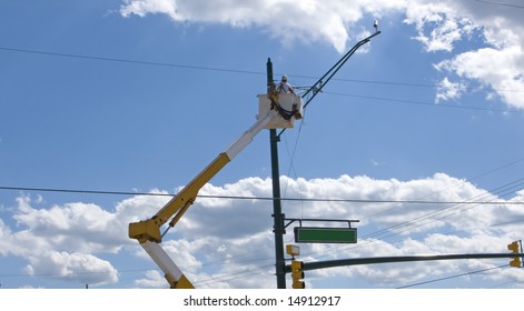 Worker Changing Light Fixture On A Post